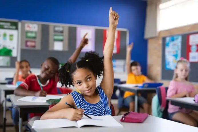 classroom of students raising their hands at school