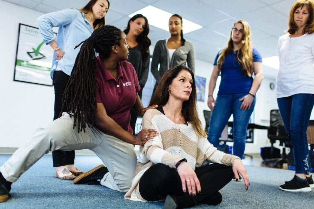 female instructor demonstrating physical safety training techniques to a small group